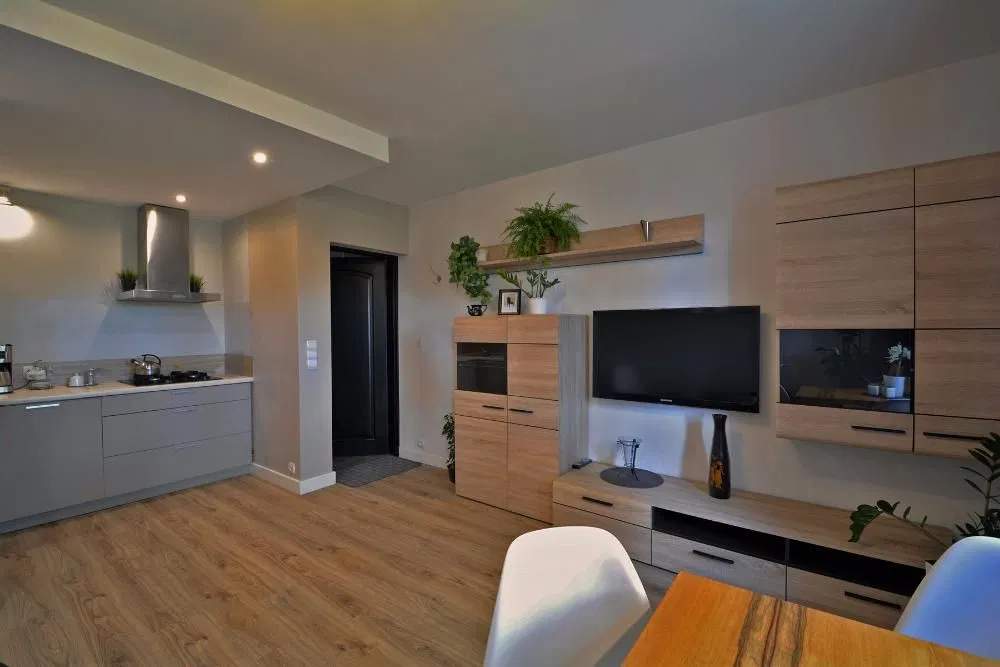 Salon z aneksem kuchennym i stołem w Apartamentach Zacisze